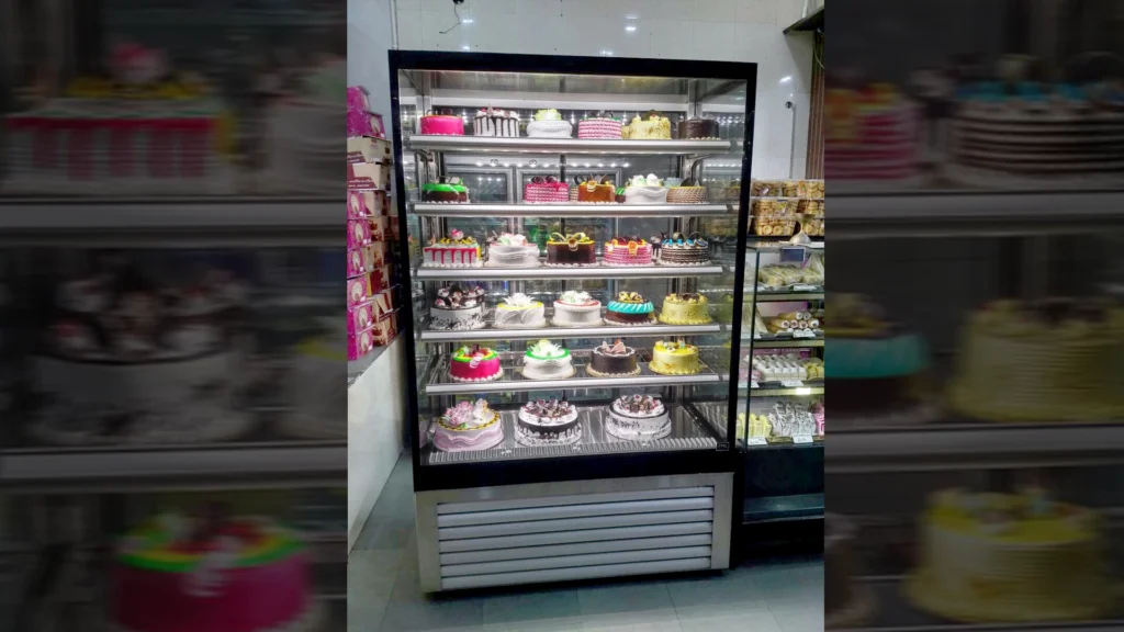 Image showing an FPG Inline Tower refrigerated display cabinet stocked with an array of beautifully decorated cakes in India.